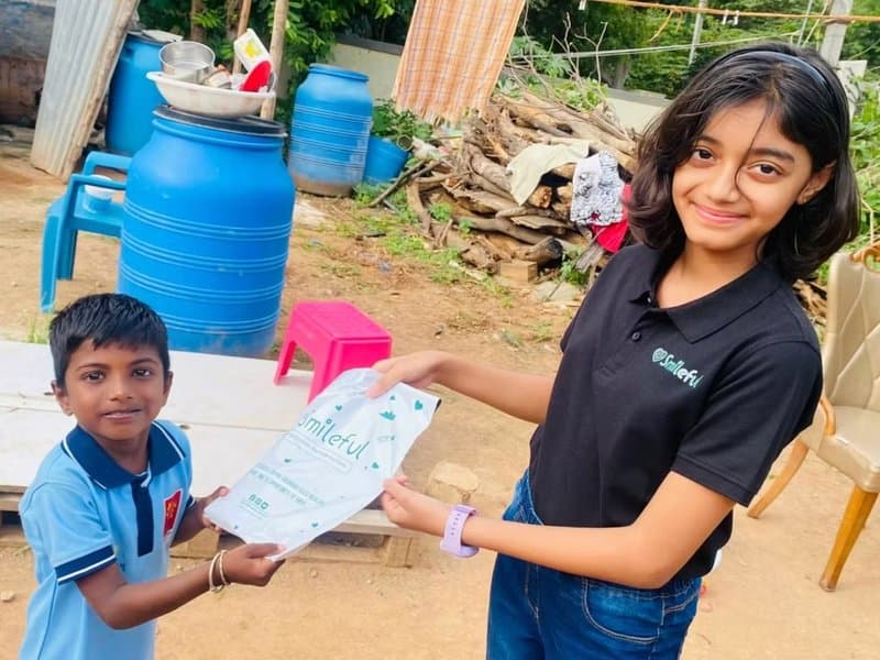 A young Smileful volunteer handing a package to a child